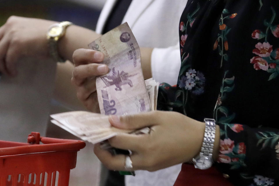 FILE - A North Korean pays money to a cashier at a supermarket in Pyongyang, North Korea, on Sept. 12, 2018. North Korea has tolerated the widespread use of more stable foreign currencies like U.S. dollars and Chinese yuan since a bungled revaluation of the won in 2009 triggered runaway inflation and public unrest. The so-called “dollarization” helped ease inflation and stabilize exchange rates, enabling leader Kim Jong Un to establish a stable hold on power after he inherited that role in late 2011. (AP Photo/Kin Cheung, File)