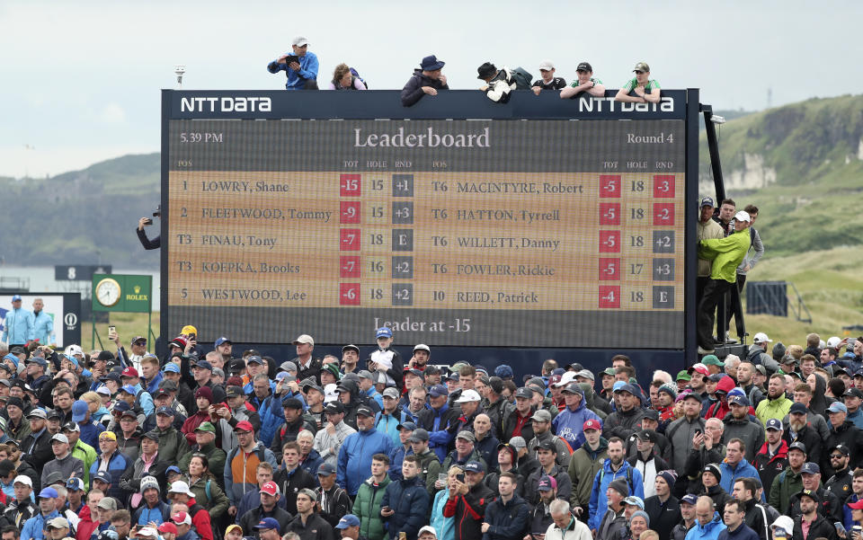 FILE - Spectators clamber on to and on top of a scoreboard as they vie to get a glimpse of Ireland's Shane Lowry and England's Tommy Fleetwood as they play during the final round of the British Open Golf Championships at Royal Portrush in Northern Ireland, Sunday, July 21, 2019. The 150th edition of the British Open is expected to attract a record-breaking crowd of 290,000 when St. Andrews hosts in July, 2022. Organizers say they received more than 1.3 million ticket applications, leading to the highest-ever number of general admission tickets being issued to fans for the world’s oldest major championship. (AP Photo/Peter Morrison, File)