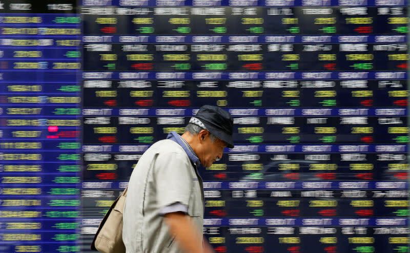 FILE PHOTO - A man walks past an electronic stock quotation board outside a brokerage in Tokyo, Japan, September 22, 2017. REUTERS/Toru Hanai