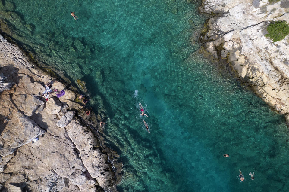 People swim in the sea at Vouliagmeni suburb, southwest of Athens, on Thursday, July 29, 2021. One of the most severe heat waves recorded since 1980s scorched southeast Europe on Thursday, sending residents flocking to the coast, public fountains and air-conditioned locations to find some relief, with temperatures rose above 40 C (104 F) in parts of Greece and across much of the region. (AP Photo/Yorgos Karahalis)