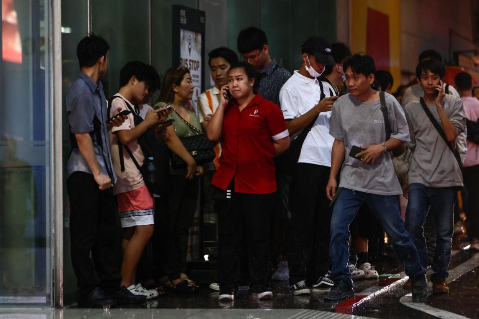 People wait for news outside the Siam Paragon shopping centre in Bangkok following a shooting incident (AFP via Getty Images)