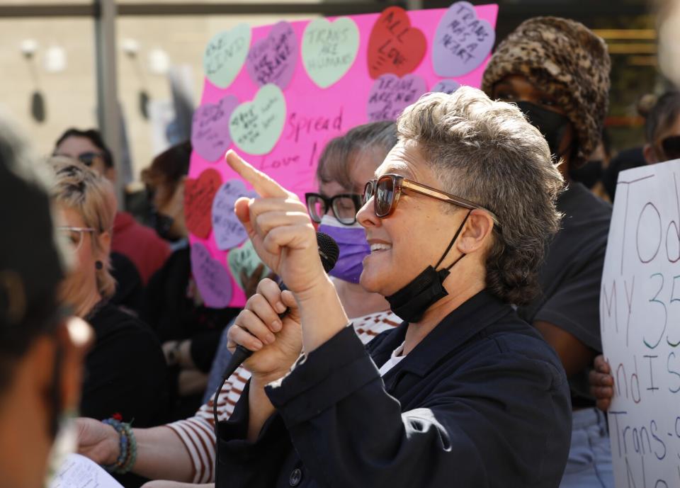 A person wearing sunglasses points at a crowd