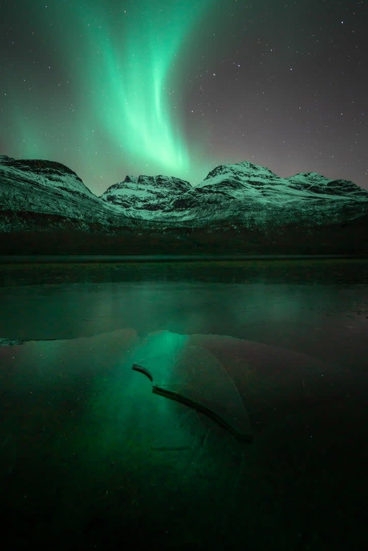 A pale green aurora over a mountain.