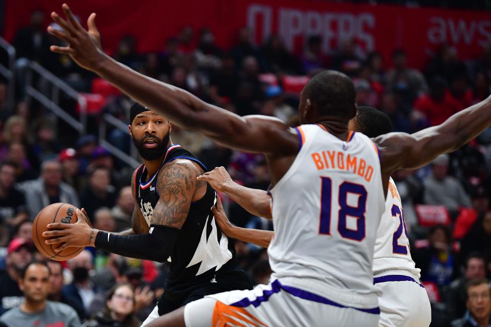 Dec 15, 2022; Los Angeles, California, USA; Los Angeles Clippers forward Marcus Morris Sr. (8) controls the ball against Phoenix Suns forward Mikal Bridges (25) and center Bismack Biyombo (18) during the first half at Crypto.com Arena. Mandatory Credit: Gary A. Vasquez-USA TODAY Sports
