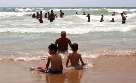 Youssef Kamoun, a 52-year-old nurse, sits near the water with his two children, Andrew, 7, and Adam, 5 at Ramlet al-Bayda public beach in Beirut