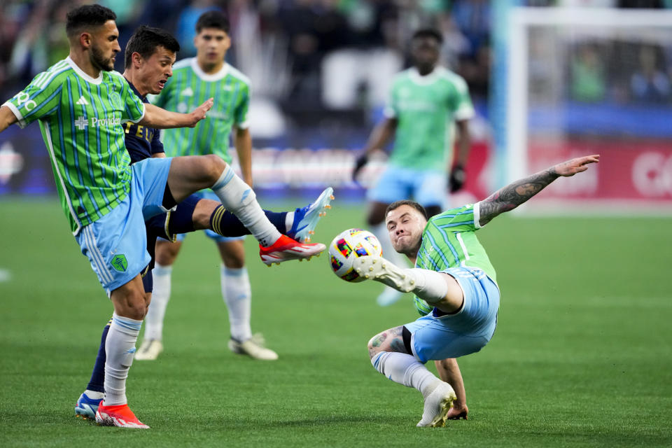 Seattle Sounders midfielder Albert Rusnák, right, tries to redirect the ball next to midfielder Cristian Roldan, left, against Vancouver Whitecaps midfielder Andrés Cubas, back left, during the first half of an MLS soccer match Saturday, April 20, 2024, in Seattle. (AP Photo/Lindsey Wasson)
