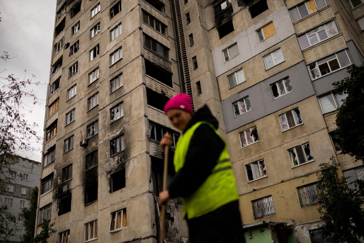 Ukrainian Olexandra Komarysta cleans the street next to a residential building damaged in a Russian bombing in Saltivka neighbourhood in Kharkiv, Ukraine, Monday, Oct. 3, 2022. 