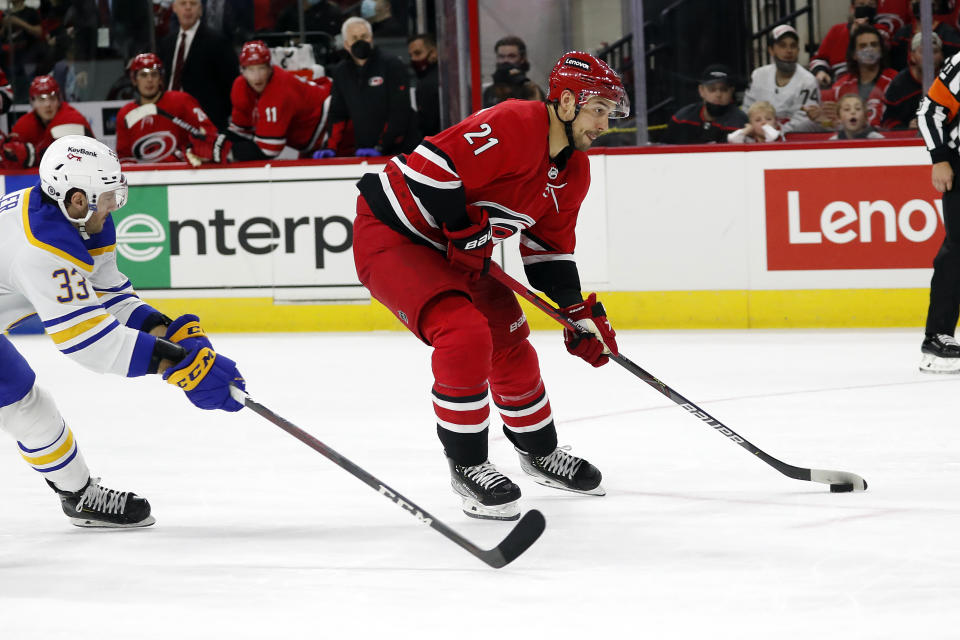 Carolina Hurricanes' Nino Niederreiter (21) skates the puck away from Buffalo Sabres' Colin Miller (33) to score a goal during the second period of an NHL hockey game in Raleigh, N.C., Saturday, Dec. 4, 2021. (AP Photo/Karl B DeBlaker)