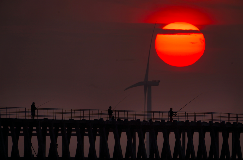 Fishermen on Blyth pier in Northumberland as the sun rises through the early morning mist.