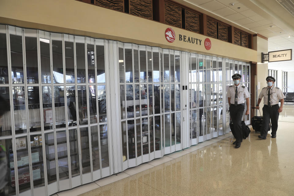 Flight crew walk past a closed duty-free shop inside the Daniel K. Inouye International Airport Thursday, Oct. 15, 2020, in Honolulu. The COVID-19 pandemic has caused a devastating downturn on Hawaii's tourism-based economy. Many stores and restaurants inside the airport remain close due the the economic crisis. (AP Photo/Marco Garcia)