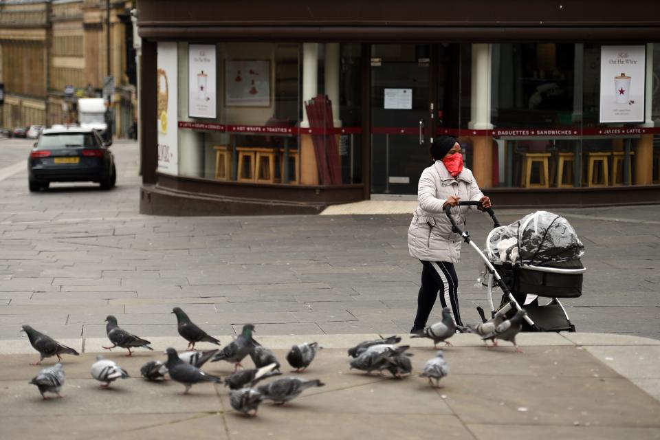 A woman wearing a scarf as a protective face mask, pushes a pram through the centre of Newcastle upon Tyne, Thursday lunchtime in north-east England on April 9, 2020 as Britain continued to battle the outbreak of new coronavirus and the governement prepared to extend the nationwide lockdown. - The disease has struck at the heart of the British government, infected more than 60,000 people nationwide and killed over 7,000, with another record daily death toll of 938 reported on April 8. A testing centre opened in Gateshead on April 9, 2020 as the government ramped up its testing of NHS staff for the new coronavirus. (Photo by Oli SCARFF / AFP) (Photo by OLI SCARFF/AFP via Getty Images)