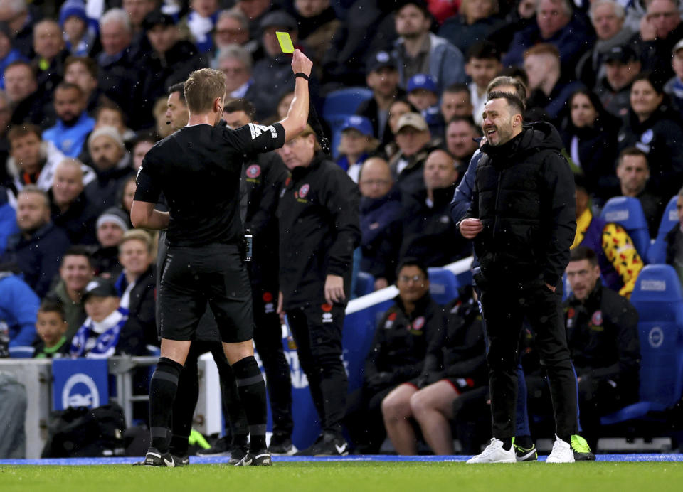 Brighton and Hove Albion manager Roberto De Zerbi, right, is shown a yellow card during the British Premier League soccer match between Brighton and Hove Albion and Sheffield United, at The AMEX, Brighton, England, Sunday Nov. 12, 2023. (Steven Paston/PA via AP)