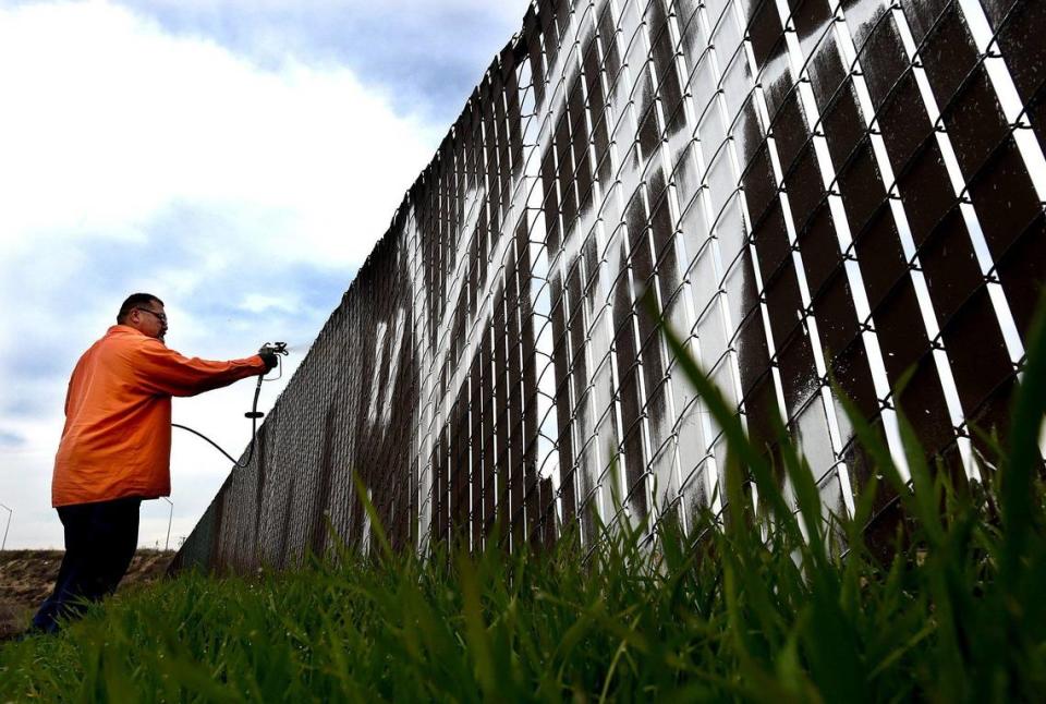 Paint gun in hand, Frank Martinez of the city’s Graffiti Abatement team, covers a tagger’s work on a fence at Ashlan and Weber, Jan. 13, 2022.