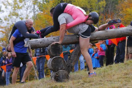 Shane Arnold and Brandy Bates clear the second obstacle ahead of Ian and Susan Bell (L) while competing in the North American Wife Carrying Championship at Sunday River ski resort in Newry, Maine October 11, 2014. REUTERS/Brian Snyder