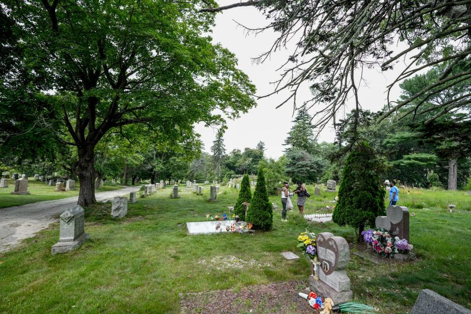 A family tends to a loved one's grave in Cranston's Oakland Cemetery.