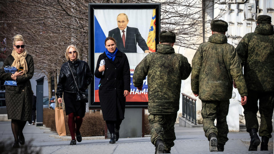 People walk in front of a poster showing Russian President Vladimir Putin and reading "The West doesn't need Russia. We need Russia!" in Simferopol, Crimea, on March 5, 2024.<span class="copyright">Stringer/AFP/Getty Images</span>