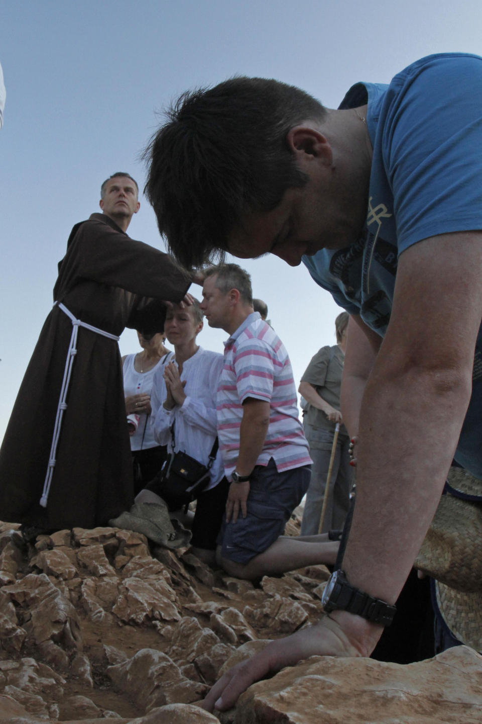 A Franciscan friar blesses pilgrims as they kneel in prayer around a statue of the Virgin Mary at the Hill Of Appearance in the southern Bosnian town of Medjugorje,160 kms south of Sarajevo, Saturday, June 25, 2011, where it is believed that the Virgin Mary showed herself and conveyed messages of peace to six children on June 25, 1981. On Friday, May 17, 2024, the Vatican will issue revised norms for discerning apparitions "and other supernatural phenomena," updating a set of guidelines first issued in 1978. (AP Photo/Amel Emric, File)