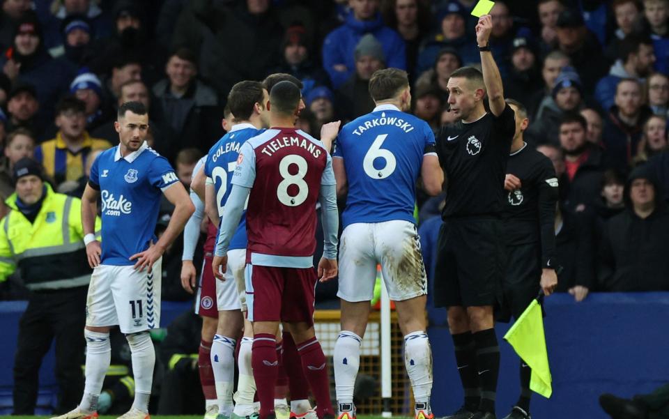 Everton's James Tarkowski is shown a yellow card by referee David Coote