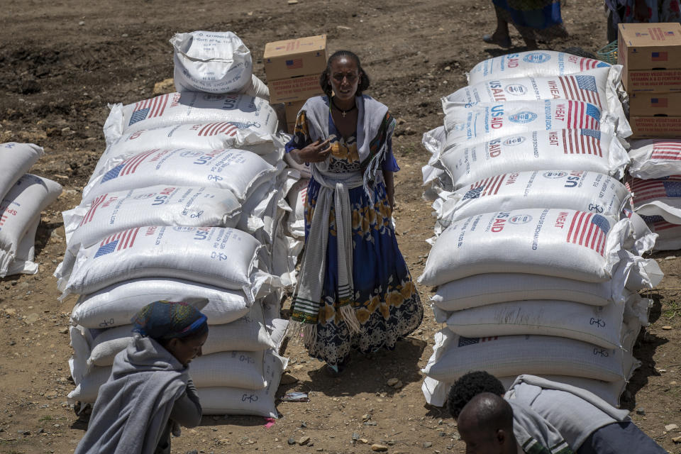 FILE - An Ethiopian woman stands by sacks of wheat to be distributed by the Relief Society of Tigray in the town of Agula, in the Tigray region of northern Ethiopia Saturday, May 8, 2021. World hunger rose in 2021 with around 2.3 billion people facing moderate or severe difficulty obtaining food -- and that was before the Ukraine war which has sparked increases in the cost of grain, fertilizer and energy, according to a U.N. report launched Wednesday, July 6, 2022. (AP Photo/Ben Curtis, File)