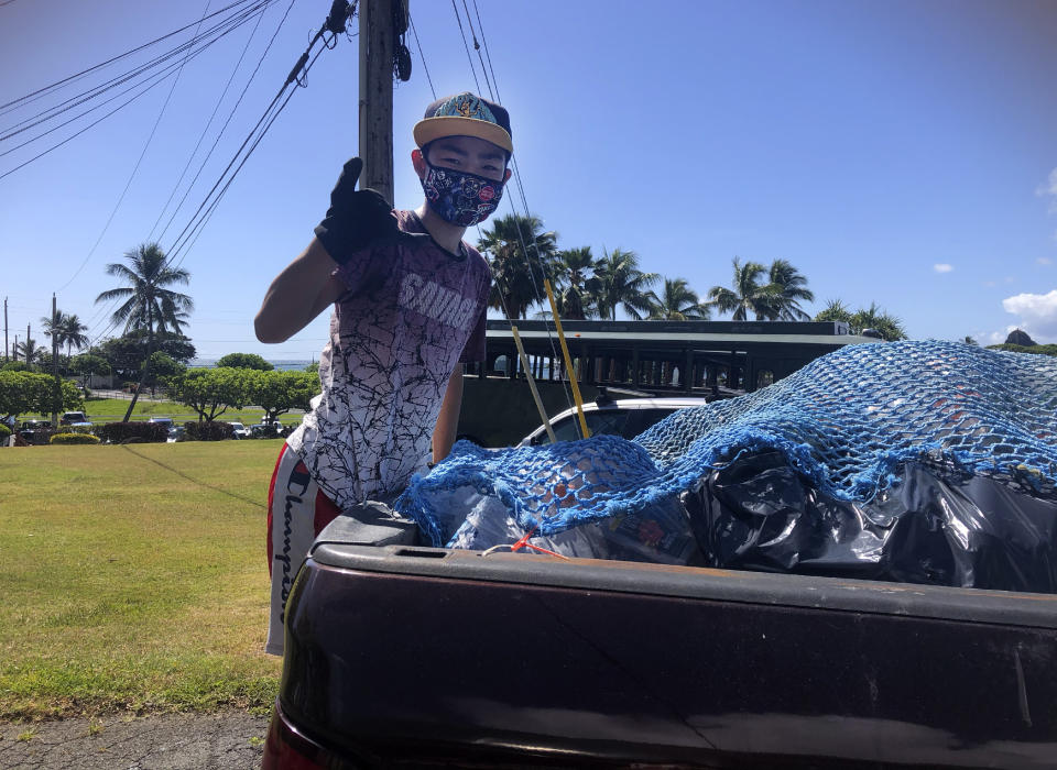 In this May 2021 photo provided by Maria Price, Genshu Price stands on the back of a truck after loading it with recyclable cans and bottles from Kualoa Ranch in Kāne'ohe, Hawaii, for his fundraiser, Bottles4College. (Bottles4College Price via AP)