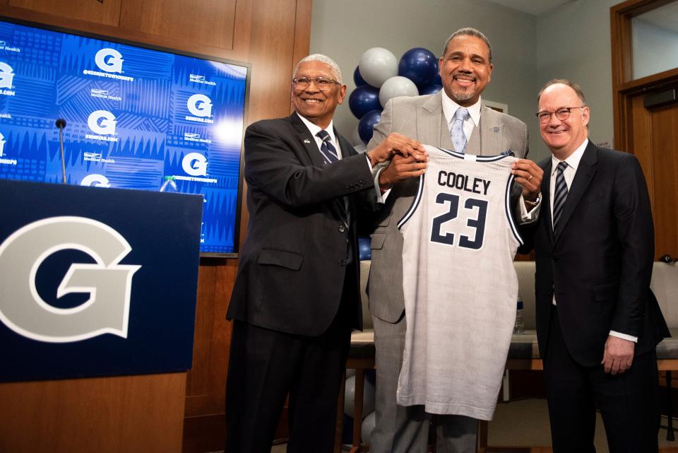 Georgetown University's president, John DeGioia, right, and director of intercollegiate athletics Lee Reed present a basketball jersey to new men's college basketball head coach Ed Cooley on Wednesday in Washington, D.C.