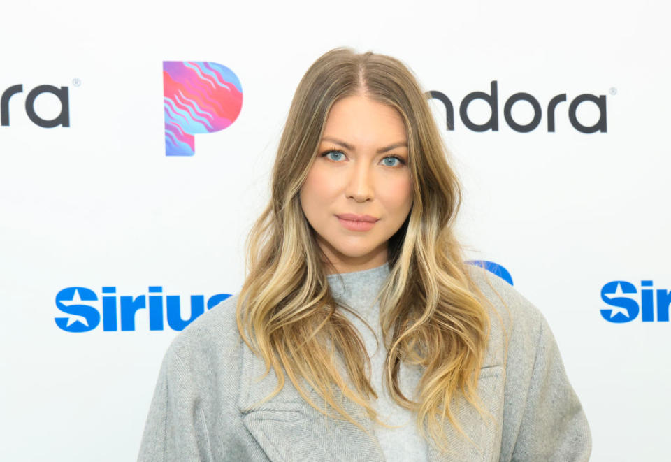 Stassi in turtleneck poses before a SiriusXM and Pandora backdrop