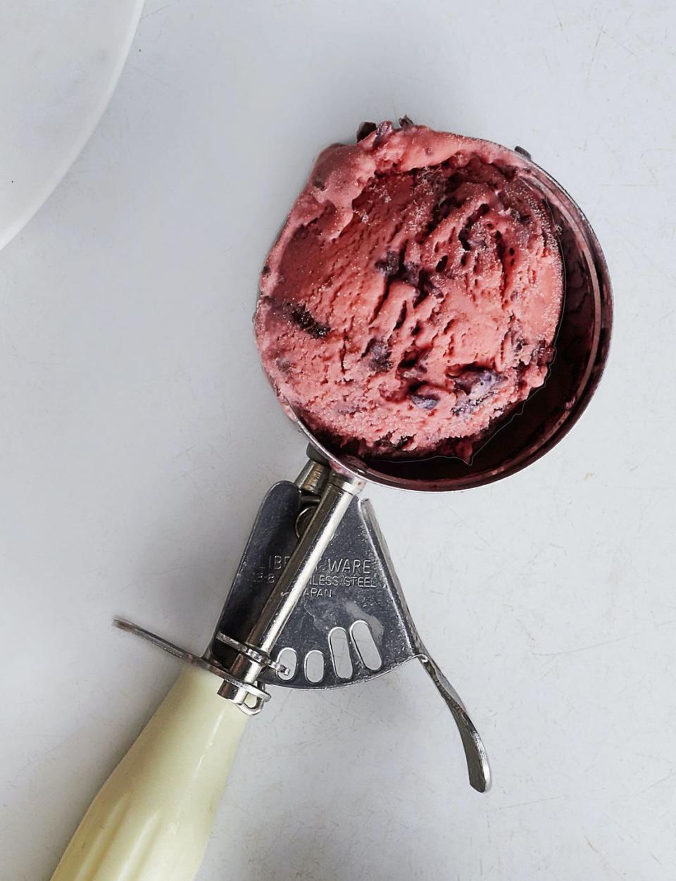 a scoop of cherries jubilee ice cream in an ice cream scooper