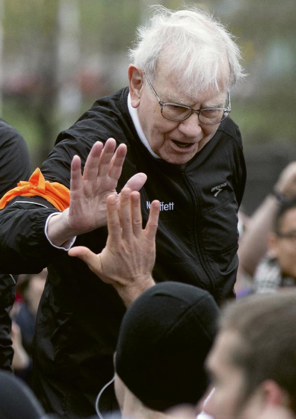 FILE - In this file photo from May 5, 2013, Investor Warren Buffett high-fives a participant in a 5K run and walk organized by the Brooks Running Company, a Berkshire Hathaway subsidiary, in Omaha, Neb. Buffett’s failure to beat the stock market in four of the past five years has inspired debate about whether Berkshire Hathaway’s 83-year-old CEO has lost his touch. Buffett and Berkshire Vice Chairman Charlie Munger are likely to face questions about the conglomerate’s performance when more than 30,000 shareholders gather for the company’s annual meeting in Omaha on Saturday. (AP Photo/Nati Harnik, file)