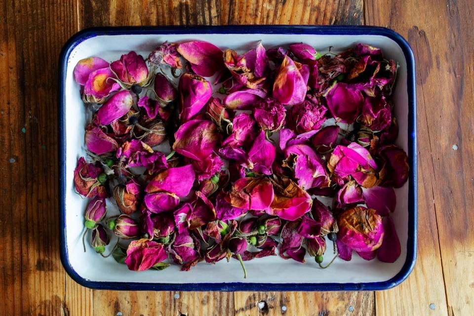 Top-down view of cut rose petals in a dish on a wooden table