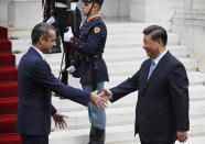 Greece's Prime Minister Kyriakos Mitsotakis, left, reaches out to shake hands with China's President Xi Jinping, right, prior to their meeting at Maximos Mansion in Athens, Monday, Nov. 11, 2019. Xi Jinping is in Greece on a two-day official visit. (AP Photos/Thanassis Stavrakis)