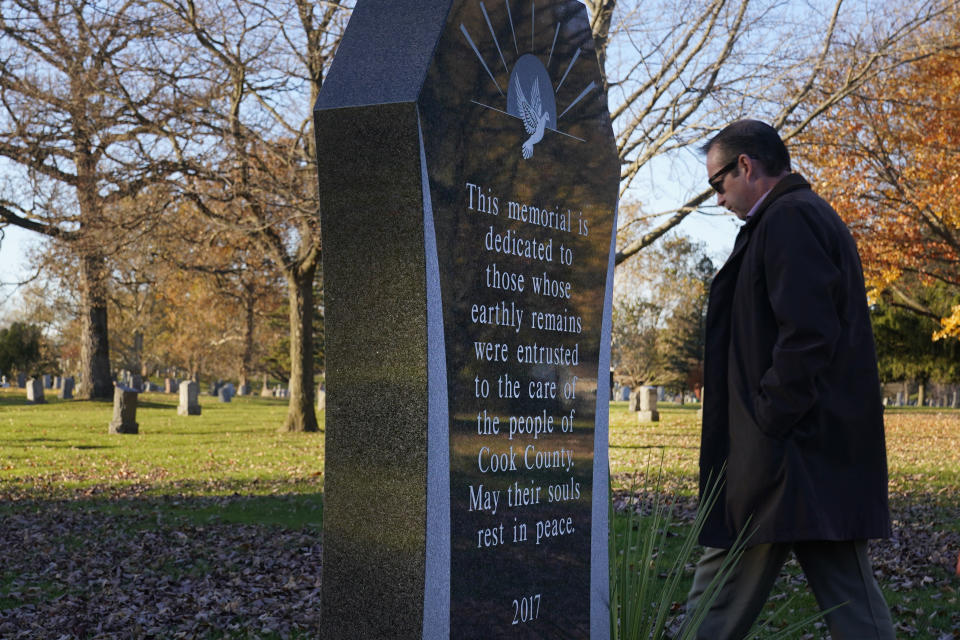 Cook County, Ill., Sheriff's Commander Jason Moran walks past a monument "dedicated to those whose earthly remains were entrusted to the care of the people of Cook County" and away from the gravesite of a person who self-identified as Seven, at the Mount Olivet Cemetery on Chicago's Far South Side Monday, Nov. 13, 2023. Eight years after Seven's death, Moran's office took up the case to identify Seven and through fingerprints taken by the coroner's office, accessing military records, Moran restored their name, Reba C. Bailey, a 75-year-old Illinois veteran missing since the 1970s. (AP Photo/Charles Rex Arbogast)