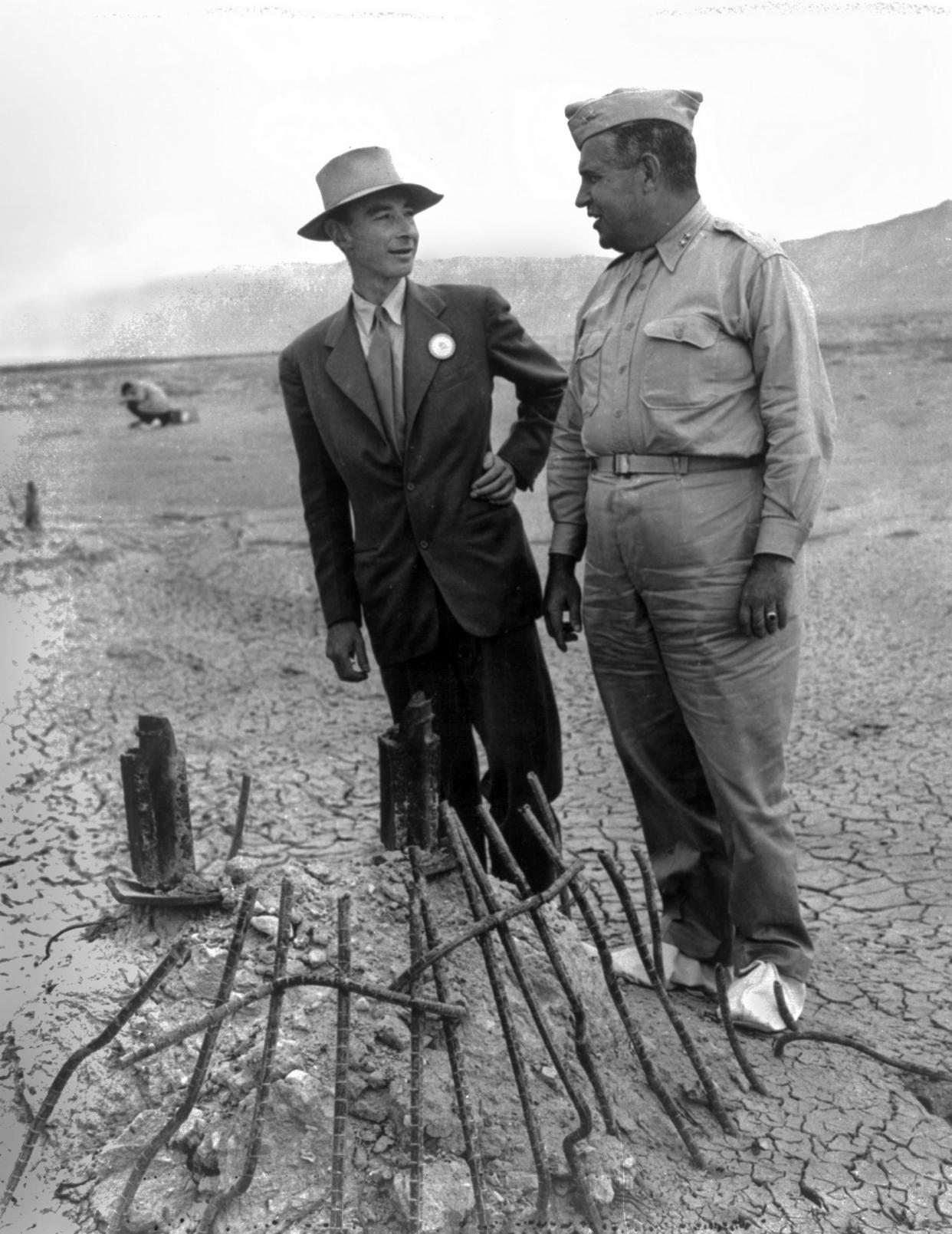 J. Robert Oppenheimer and Gen. Leslie Groves examine the remains of one the bases of the steel test tower at the atomic bomb test site in September 1945.