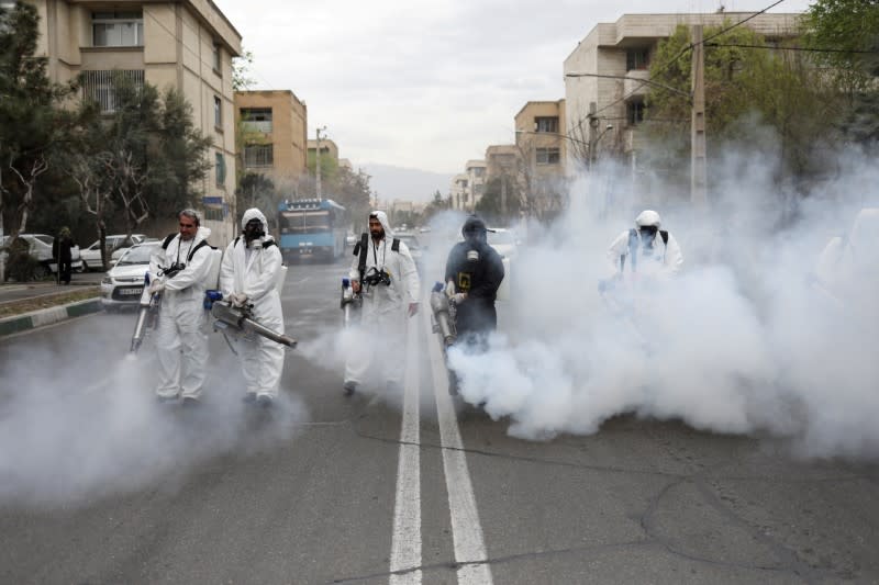 FILE PHOTO: Members of firefighters wear protective face masks, amid fear of coronavirus disease, as they disinfect the streets, ahead of the Iranian New Year Nowruz, March 20, in Tehran