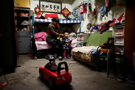 Huan feeds her son Peijun in her family's hut at a recycling yard at the edge of Beijing, China, October 20, 2016. REUTERS/Thomas Peter/Files