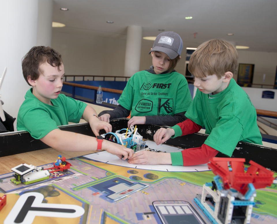 Greyson Brewer, 8, of Randolph, Julian Wynn, 10, of Kent, and Sean Tompkins, 9, of Cuyahoga Falls are members of the Super Electric team and demonstrate how their robot works during a youth robotics tournament at Kent State University on Saturday.