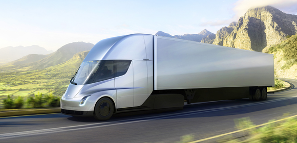 Tesla Semi traveling on a rural road with mountains in background.