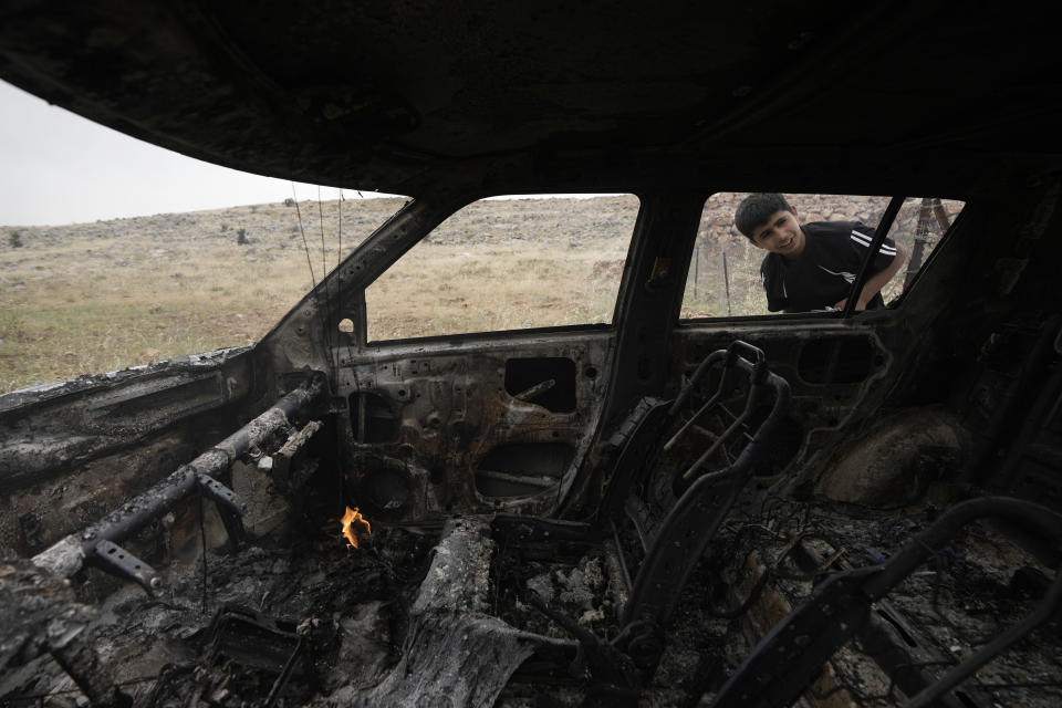 A Palestinian child inspects a burnt car, which farmers say was set on fire by Israeli settlers, in the village of al-Mughayyir near the West Bank city of Ramallah, Friday, May 26, 2023. Jewish settlers attacked Palestinian farmers and torched five vehicles in the village, the official Palestinian news agency reported. It added that five farmers were injured when settlers beat them. There was no immediate comment from the Israeli military.(AP Photo/Majdi Mohammed)