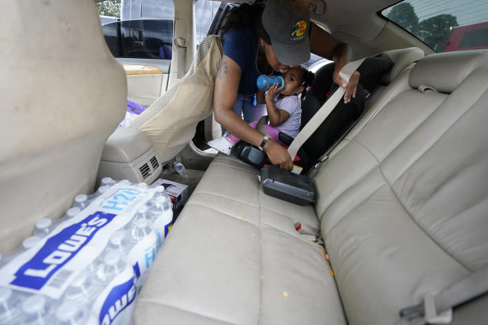 Shantia Crumb straps her daughter Jayda into her car seat after receiving two cases of water at a community drive-thru water distribution site in south Jackson, Miss., Sept. 7, 2022. A boil-water advisory has been lifted for Mississippi's capital, and the state will stop handing out free bottled water on Saturday. But the crisis isn't over. Water pressure still hasn't been fully restored in Jackson, and some residents say their tap water still comes out looking dirty and smelling like sewage. (AP Photo/Rogelio V. Solis)