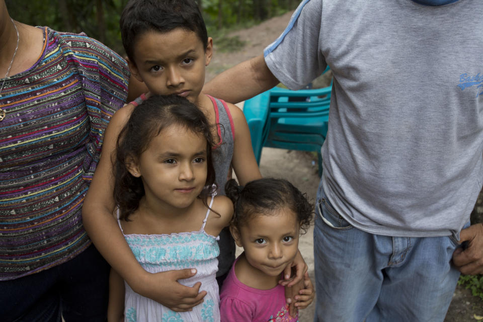 In this Nov. 2, 2018 photo, 3-year-old Brithani Lizeth Cardona Orellana, bottom right center, stands with her 5-year-old sister Janeisy Nicolle and brother 9-year-old brother Kenner Alberto, flanked by their aunt and uncle at their home in San Pedro Sula, Honduras. The children's parents are hundreds of miles and two countries away, making their way toward the United States with thousands of others in a migrant caravan. (AP Photo/Moises Castillo)