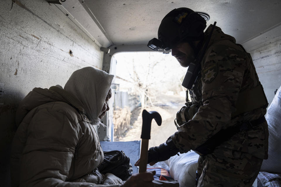 A Ukrainian police officer helps en elderly woman as she evacuates to safe areas in Chasiv Yar near Bakhmut, Ukraine, Saturday, March 4, 2023. (AP Photo/Evgeniy Maloletka)