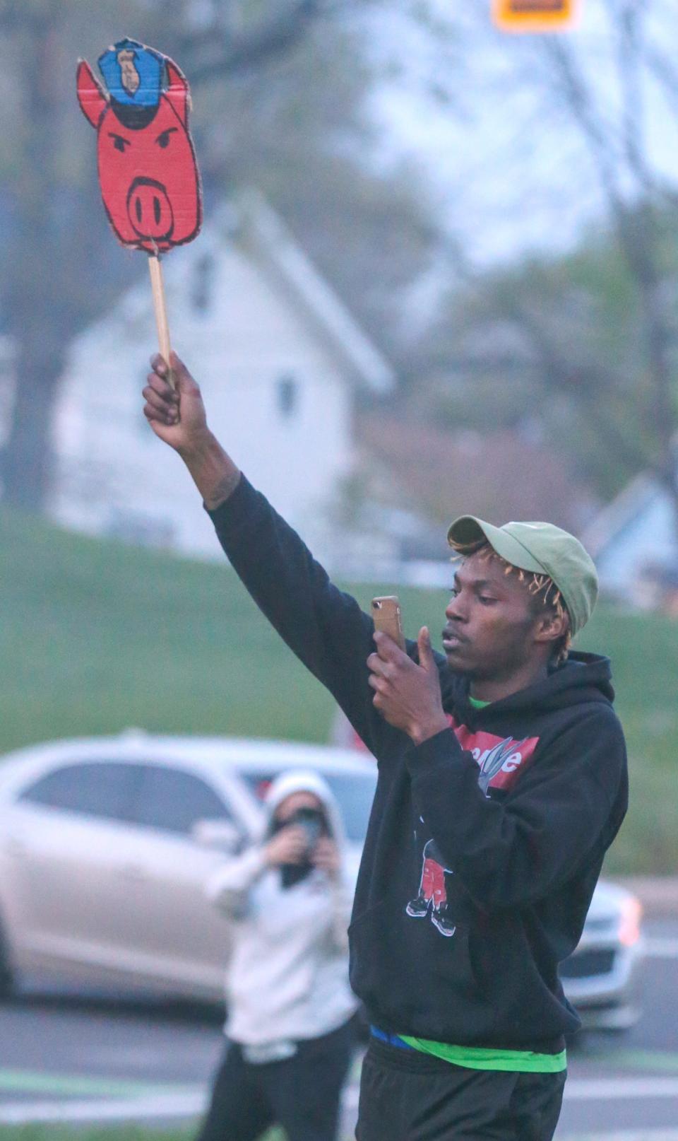 A protester holds a sign during an April 19 protest on Copley Road in which police and deputies deployed pepper spray and tear gas to disperse the crowd.