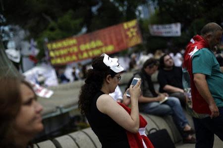 A protester uses her mobile device as she walks at Gezi Park on Taksim Square in Istanbul June 6, 2013. REUTERS/Stoyan Nenov