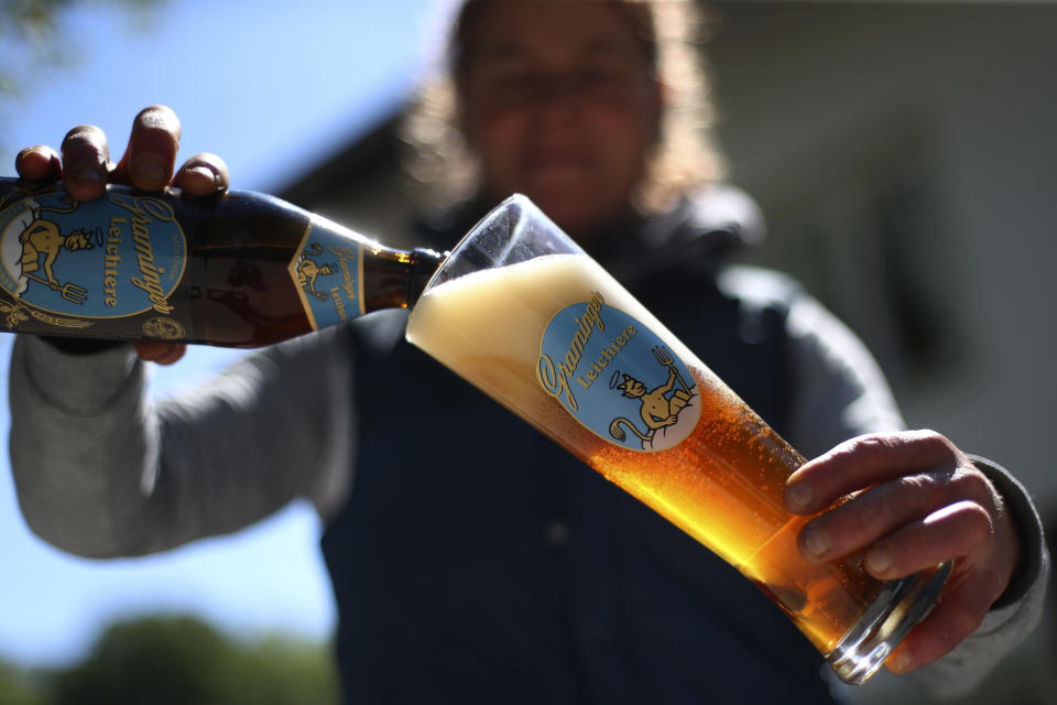 In this photo taken Thursday, May 7, 2020 brewery daughter Iris Detter pours a beer outside her 120 year old family brewery and traditional Bavarian restaurant in Altoetting, Germany. The 'Graminger Weissbraeu' brewery, which has been in the same family for a century, is preparing to welcome guests back to its restaurant for the first time in two months — with new rules and fears for the future. (AP Photo/Matthias Schrader)