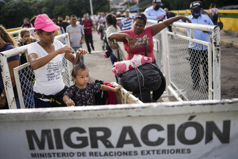 Betania Arteaga plays with her son's hair as they wait to use the Simon Bolivar International Bridge to cross between San Antonio, Venezuela, and Cucuta, Colombia, Friday, Aug. 5, 2022, on the border that is open to pedestrian traffic but closed to cargo trucks. The border will gradually reopen after the two nations restore diplomatic ties when Colombia's new president is sworn-in on Aug. 7, according to announcement in late July by Colombia's incoming Foreign Minister Alvaro Leyva and Venezuelan Foreign Minister Carlos Faria. (AP Photo/Matias Delacroix)