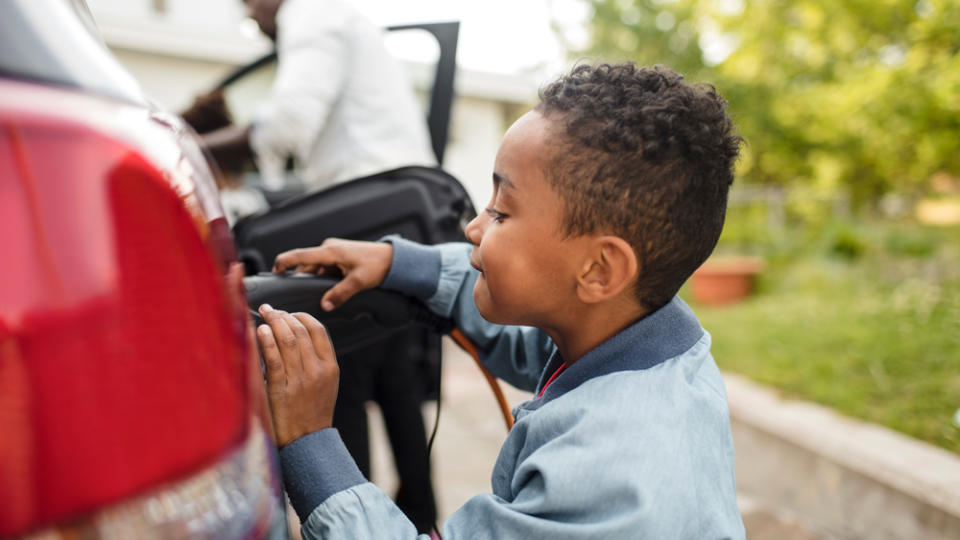 A young boy helps charge his family's electric car.