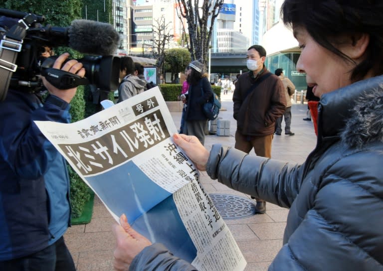 A woman reads an extra edition newspaper in Tokyo about North Korea's rocket launch