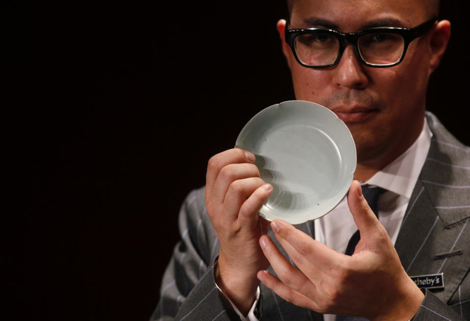 Nicolas Chow, Sotheby’s Asia Deputy Chairman, holds the Chinese Song Dynasty ceramics Ruyao Washer at the Sotheby's auction in Hong Kong Wednesday, April 4, 2012. The 900-year-old dish smashed the world record for Chinese Song Dynasty ceramics sold at auction, fetching US$26.7 million. (AP Photo/Kin Cheung)