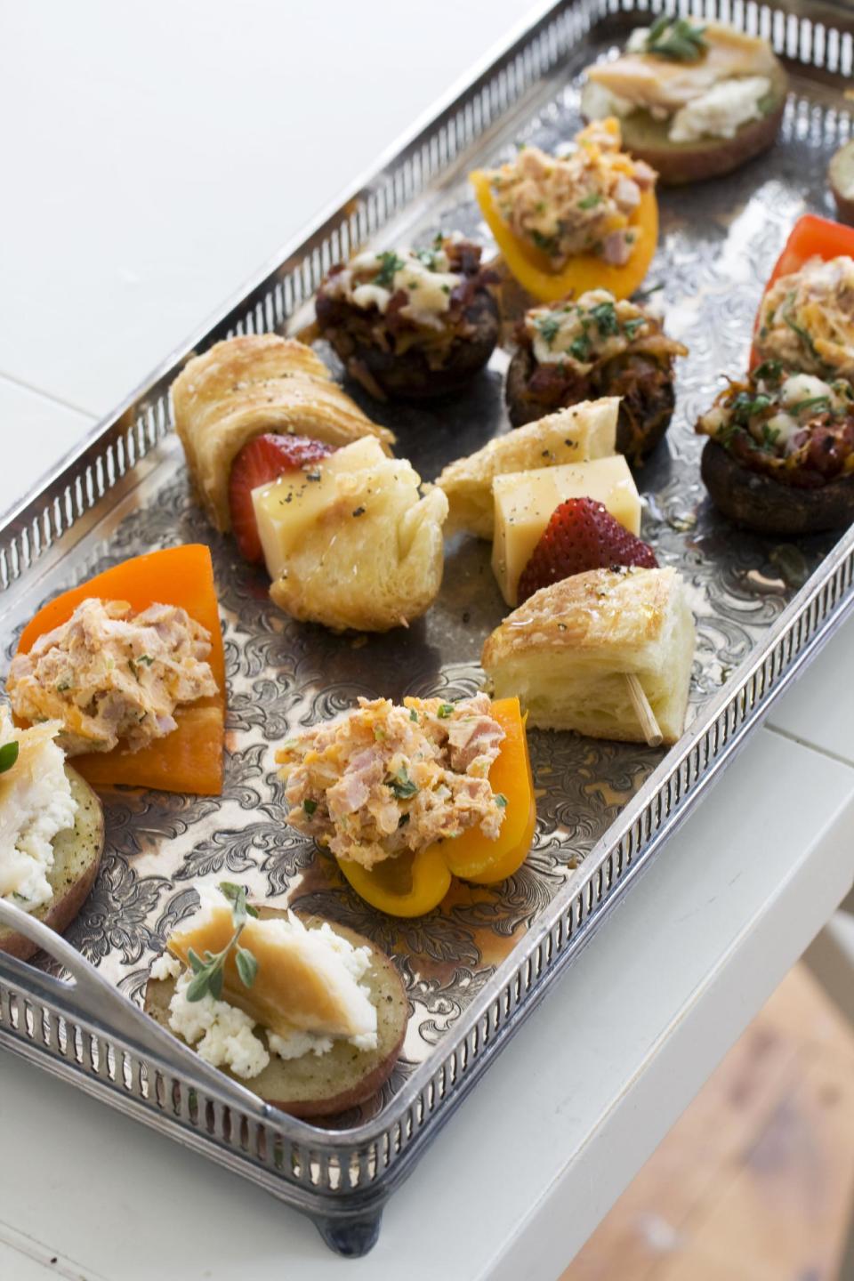 In this image taken on April 22, 2013, front to back, smoked schmeared potatoes, stuffed baby bell peppers, strawberry croissant skewers, and chorizo hash stuffed mushroom caps, are shown served on a tray in Concord, N.H. (AP Photo/Matthew Mead)