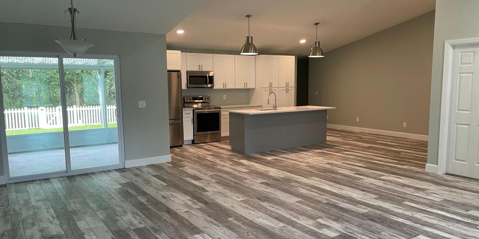 A kitchen with white and brown floors and a sliding door window to the outside.