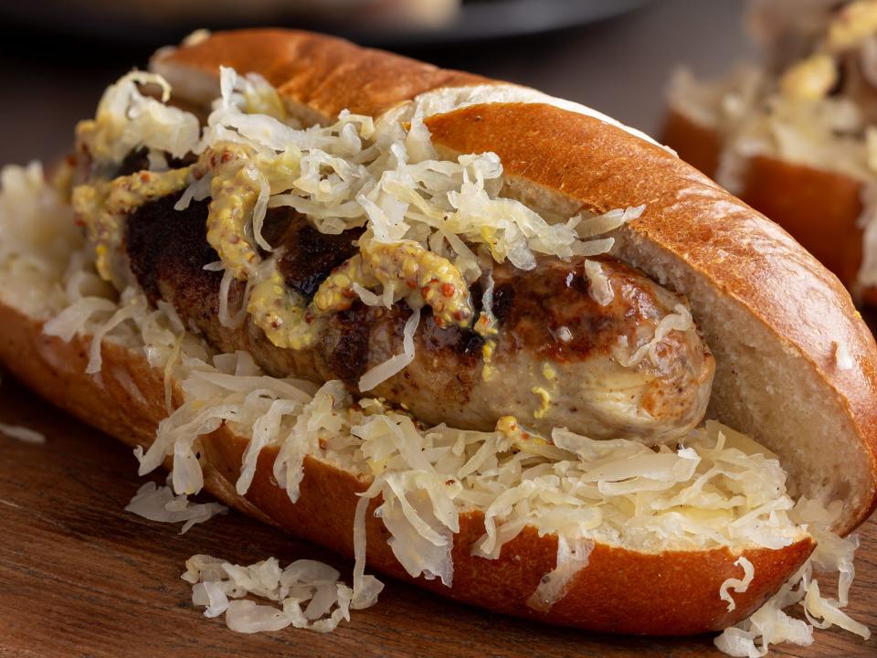 bratwurst sausage with sauerkraut and dijon mustard on a bun